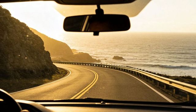 Driving along sunset coastal highway curving around cliffs overlooking ocean