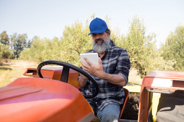 Man using digital tablet in tractor on a sunny day