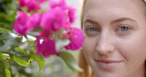 Smiling Woman in Garden Admires Vibrant Bougainvillea