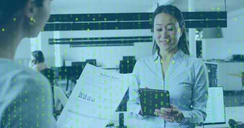 Holding tablet and reviewing report in modern office with green binary data overlay for teamwork