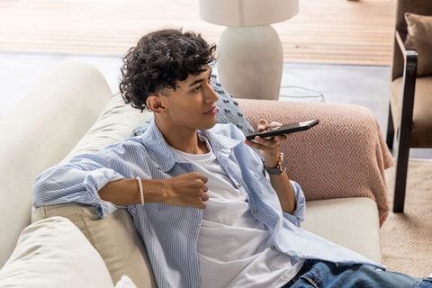 Man communicating on smartphone while reclining on sofa at home