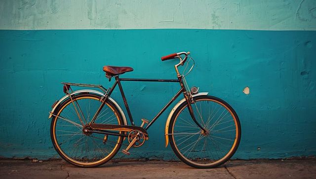 Vintage city bicycle leaning against turquoise wall with leather saddle and retro headlamp