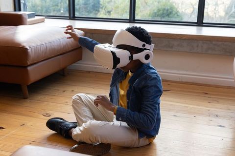 African-American Boy Exploring Virtual Reality Wearing Headset in Living Room