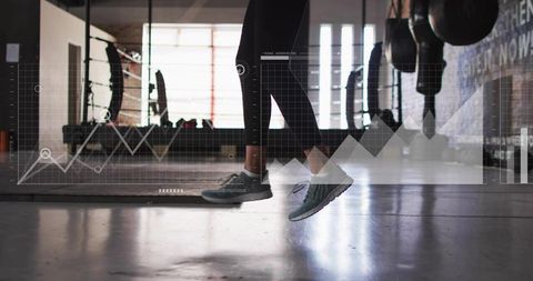 Jumping woman wearing black leggings and gray sneakers over gym mat with data overlay