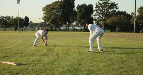 Two Cricketers Fielding Together on Green Outfield During Casual Practice and Team Drill