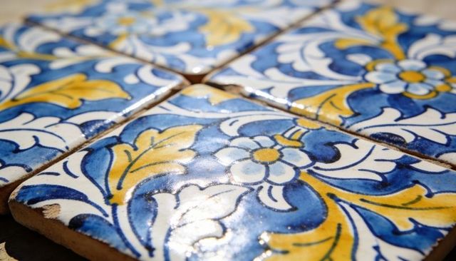 Hand-painted blue and yellow glazed ceramic tiles featuring floral motif and chipped corner