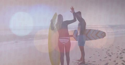 Joyful Surfer Friends Celebrating by Beach at Sunrise