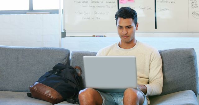 Young Man Working on Laptop in Modern Office Setting - Download Free Stock Images Pikwizard.com