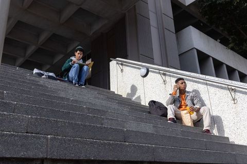 College Students Studying and Relaxing on Urban Concrete Steps with Backpacks and Snacks