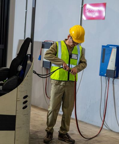 Warehouse Worker Connecting Cables at Industrial Charging Station
