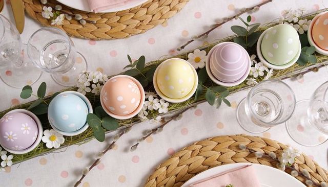 Pastel easter eggs centerpiece on moss tray with white egg cups and spring floral accents