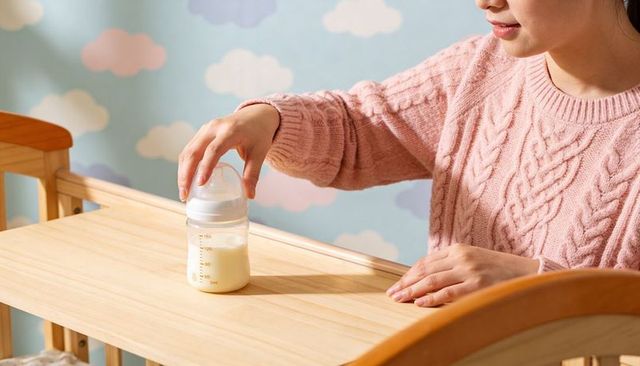 Caregiver placing baby bottle on wooden changing table in pastel cloud nursery