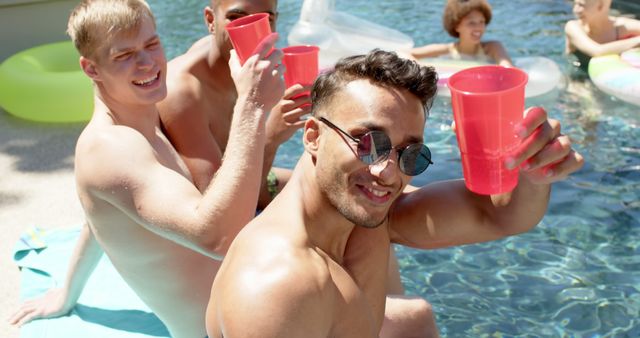 Portrait of happy diverse friends playing and drinking drinks at pool party in summer. Friendship and spending quality time at home concept.