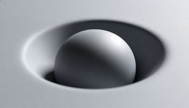 Matte sphere nesting in shallow concave on textured monochrome plane with soft shadow