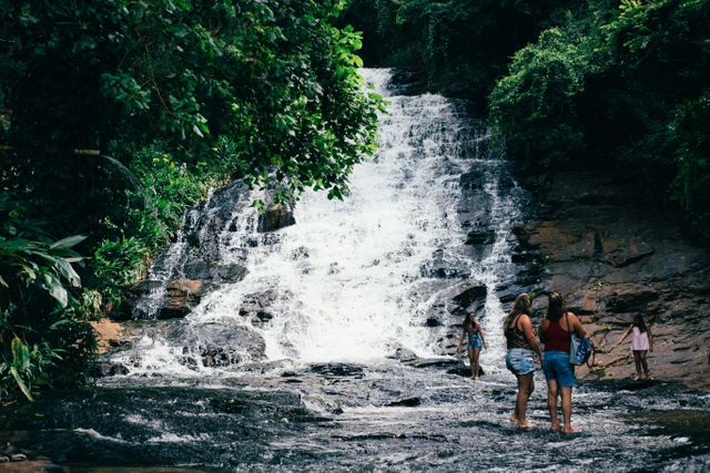 People are enjoying a refreshing adventure at a stunning waterfall deep in a lush tropical jungle. Ideal for use in travel articles, adventure blogs, nature tourism promotions, or environmental awareness campaigns to highlight the beauty of natural landscapes and the joy of outdoor activities.