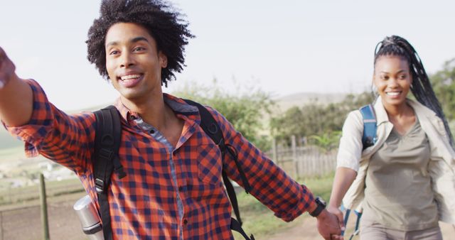 Happy african american couple with backpacks, hiking together on sunny day, slow motion. Lifestyle, countryside and nature concept.
