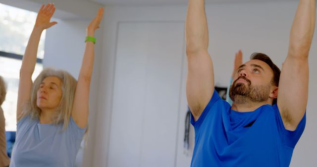 Senior Woman and Bearded Man Practicing Yoga Indoors with Raised Arms - Download Free Stock Images Pikwizard.com