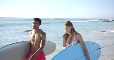 Two Surfers Walking on Beach With Surfboards on a Sunny Day