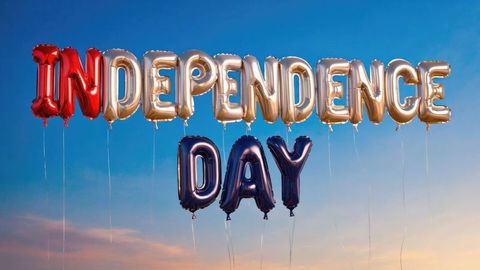 Metallic foil balloons spelling 'independence day' against dusky sky