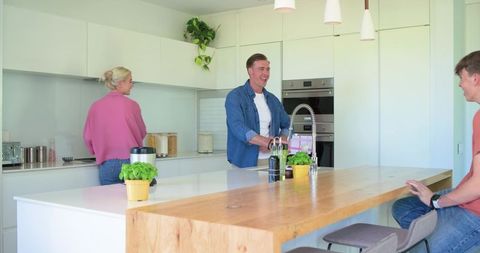 Family enjoying bright modern kitchen with wooden island, stainless faucet and herbs together