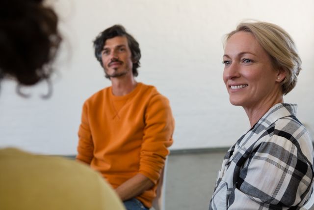 Woman smiling and engaging with friends in an art class. Ideal for use in content related to community activities, adult education, creative hobbies, and social interactions.