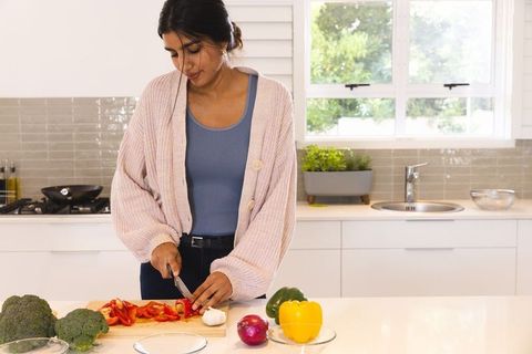 Asian woman preparing fresh bell peppers in modern kitchen