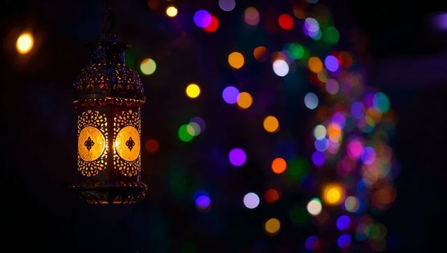 Ornate moroccan lantern casting warm amber light with multicolored bokeh background
