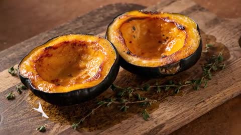 Roasted acorn squash halves gleaming with caramelized glaze and thyme on rustic board