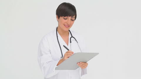 Smiling Doctor Writing on Clipboard in Medical Setting