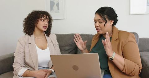 Two professionals collaborating on laptop in modern living room during consultation