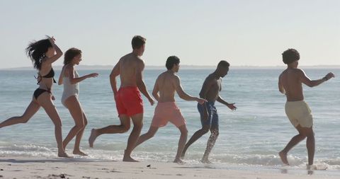 Diverse group of friends enjoying at the beach, slow motion fun