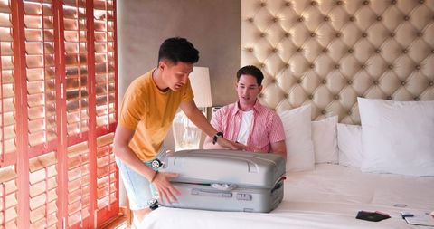 Same-Sex Couple Preparing for Getaway with Packed Suitcase
