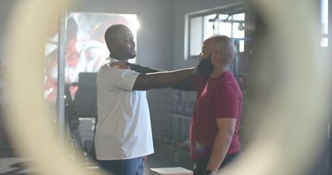 Coach guiding client through posture correction during kettlebell training in bright fitness studio