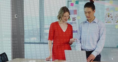 Collaborating over laptop and tablet in modern office with digital code overlay