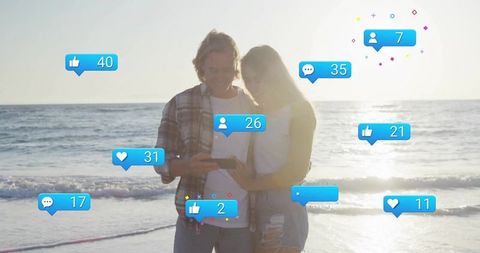 Couple with Social Media Alerts Bathed in Sunset Glow at Beach