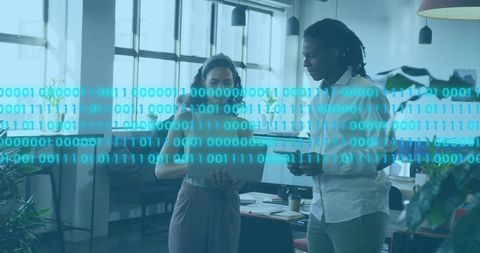 Young professionals collaborating over tablet with binary data overlay in modern office