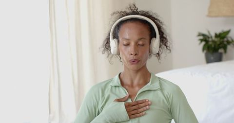 Woman practicing mindfulness using headphones in modern interior