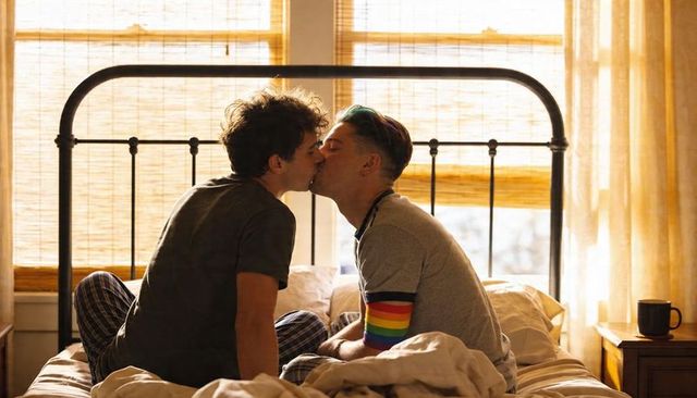 Morning Kiss Two Men on Bed Wearing Rainbow Sleeve Pajamas Warm Sunlit Romance
