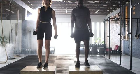 Diverse workout partners performing step-ups in industrial gym setting