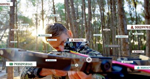 Hunter in camouflage aiming crossbow with digital overlays in forest