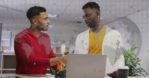 Two colleagues collaborating over laptop and documents in modern open-plan office