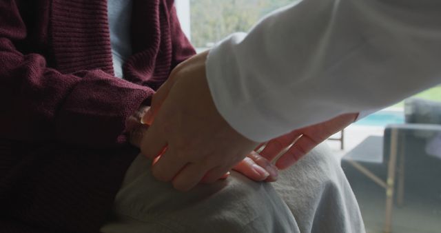 Doctor holding hands with an elderly patient in a clinic symbolizing support and empathy. Ideal for use in healthcare advertisements, geriatric care services, medical articles, and promotional material for medical facilities showing compassionate patient care.