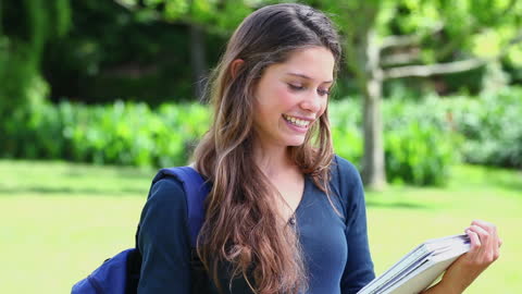 Smiling Woman Reading Notebook in Park