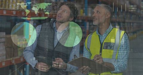 Diverse workforce analyzing data with digital interfaces in warehouse
