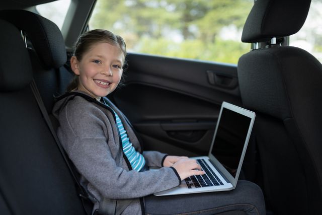 Portrait of teenage girl using laptop in the back seat of car