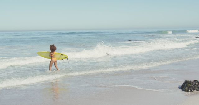 Biracial woman walking on sea and holding surfboard. Summer, relaxation, vacation, happy time, summer time.