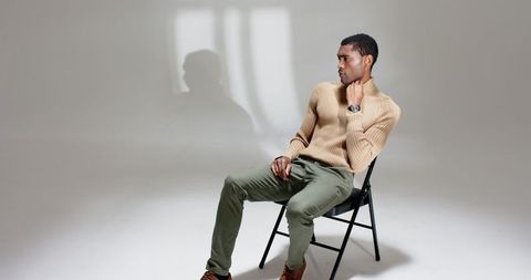 Elegant man in turtleneck with wristwatch posing on chair