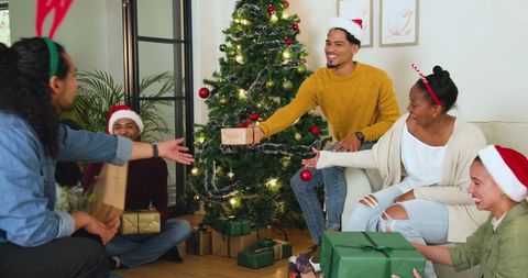 Festive friends exchanging gifts by christmas tree