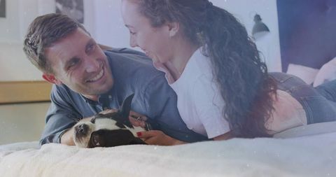 Smiling couple relaxing with adorable dog on cozy bed