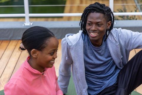 African american teenagers chatting and smiling after rooftop workout in casual sportswear